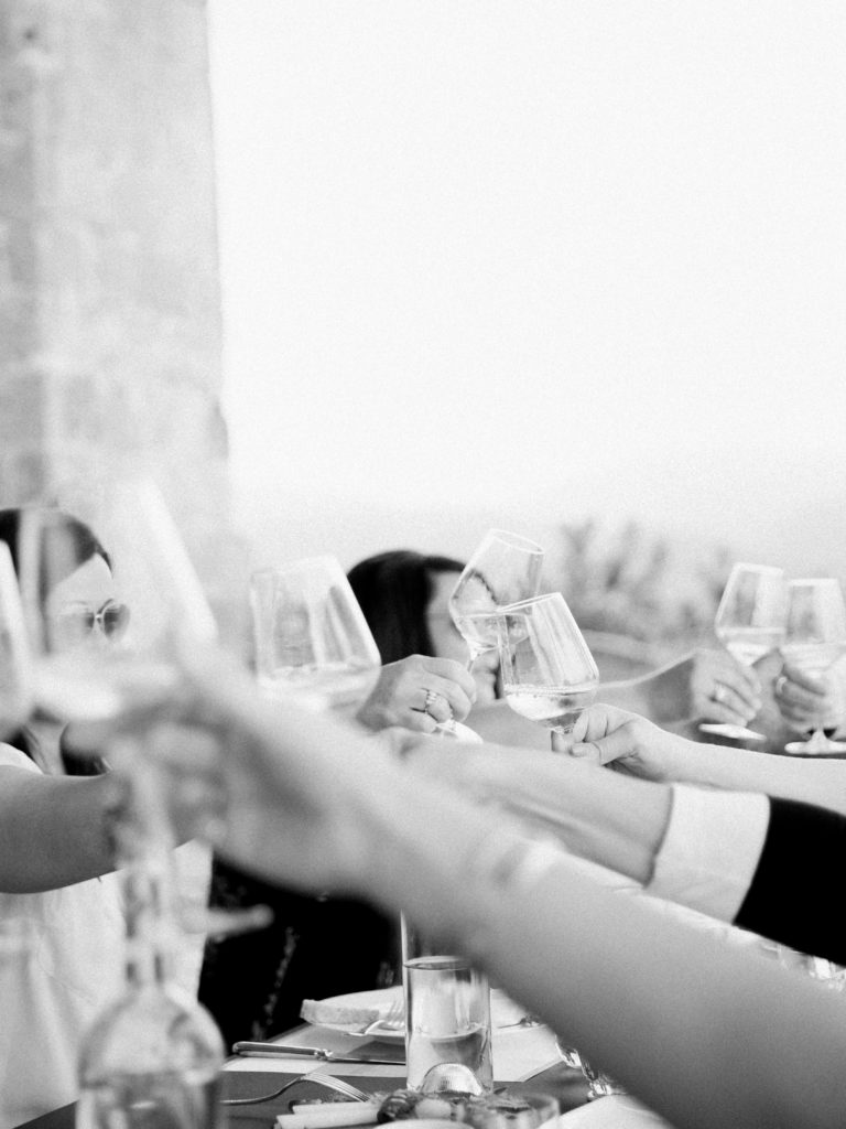 Black and white photo of people toasting wine glasses in italy | Photo by Josie Derrick 