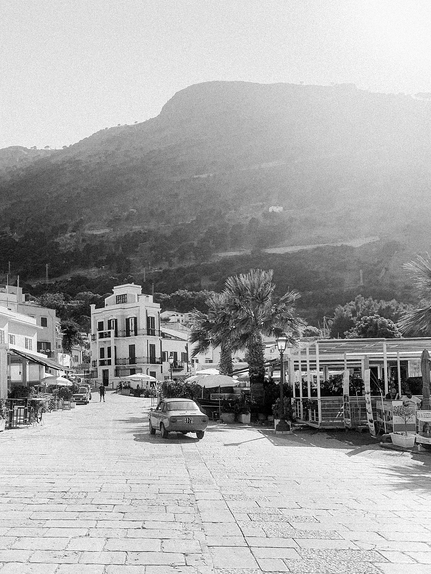 Black and white photo of an Italian car driving through Castellammare del Golfo | Photo by Josie Derrick 