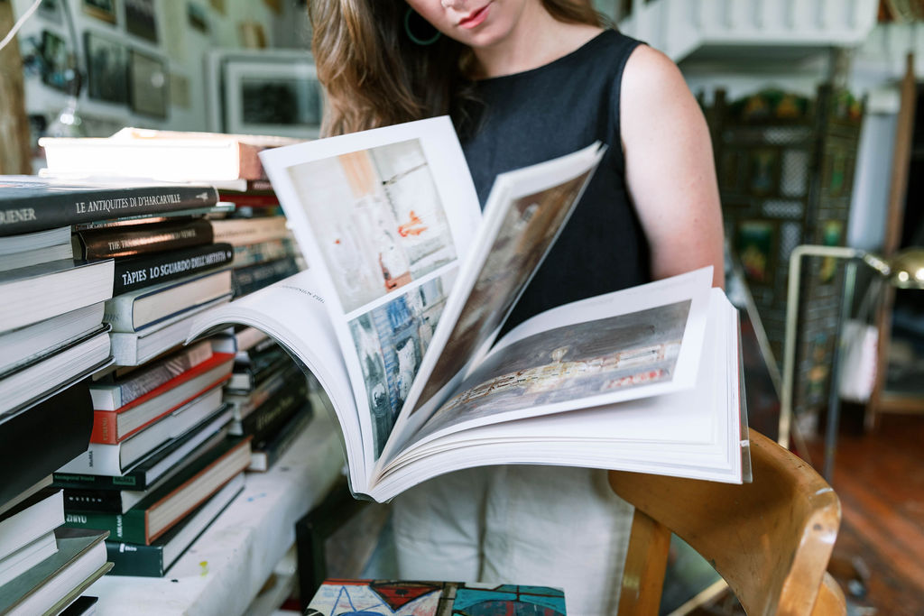 Woman flipping through an art book standing in an art studio | Image by Josie Derrick